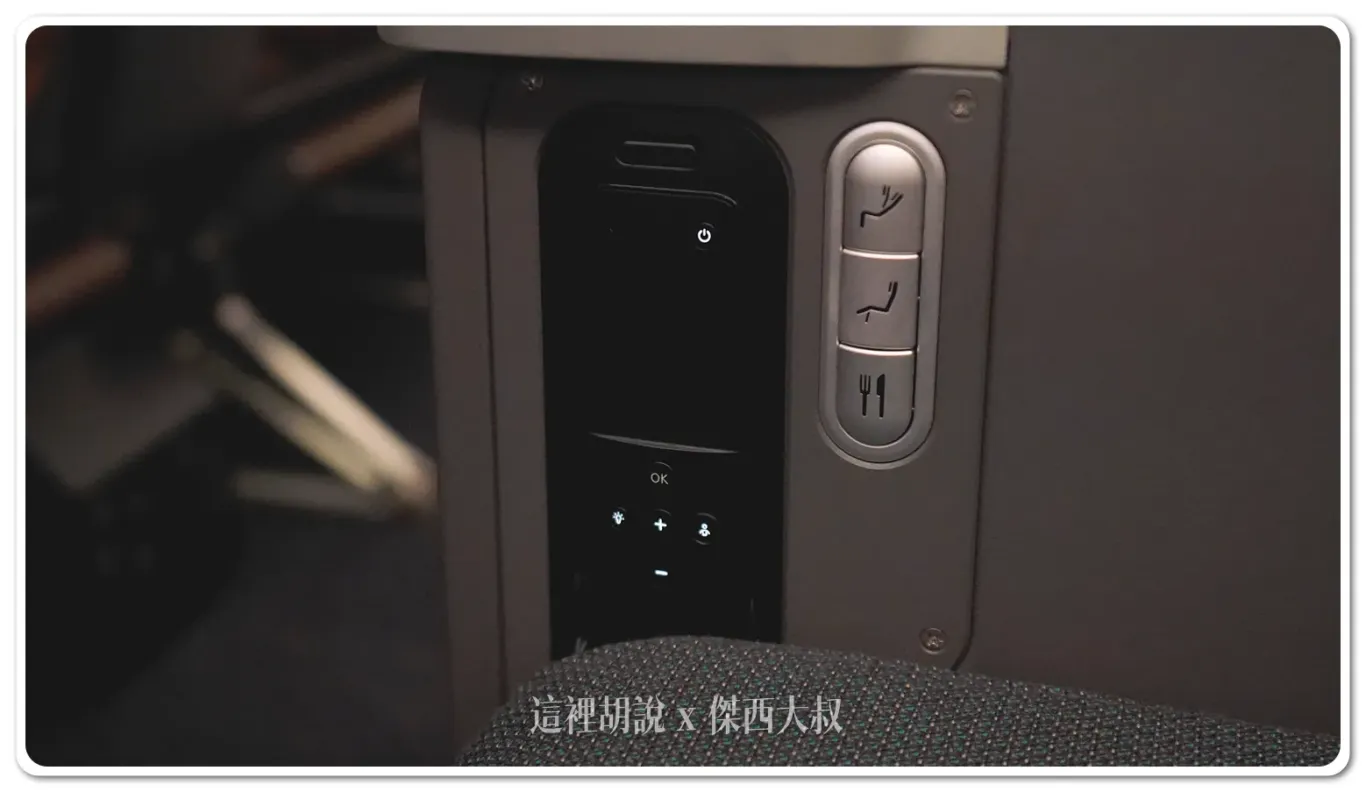 The seat control has three buttons, arranged from top to bottom: seat recline control, leg rest, and tray table. On the side is the entertainment system remote, which is generally unnecessary since the system can be fully controlled via the touchscreen.