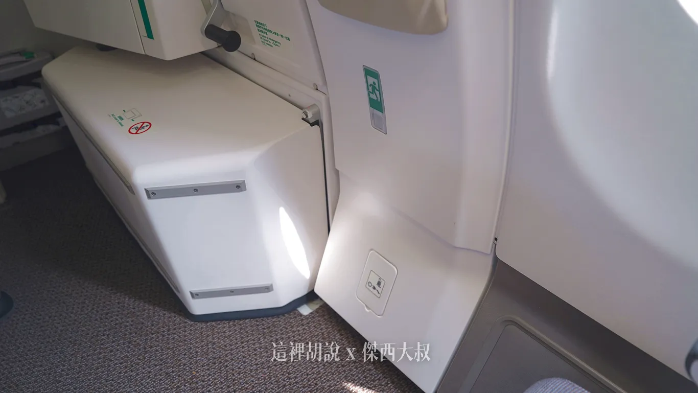 緊急出口K排前方的空位，左側隆起物為逃生滑梯，不能放置物品以及坐下坐在緊急出口的旅客有義務制止其他人觸碰