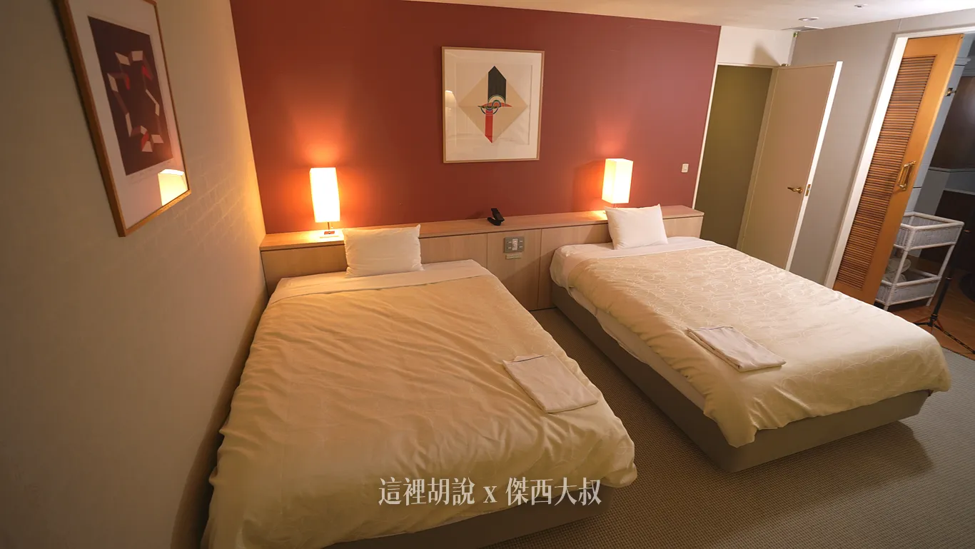 Two beds, with a passage to the bathroom on the side.