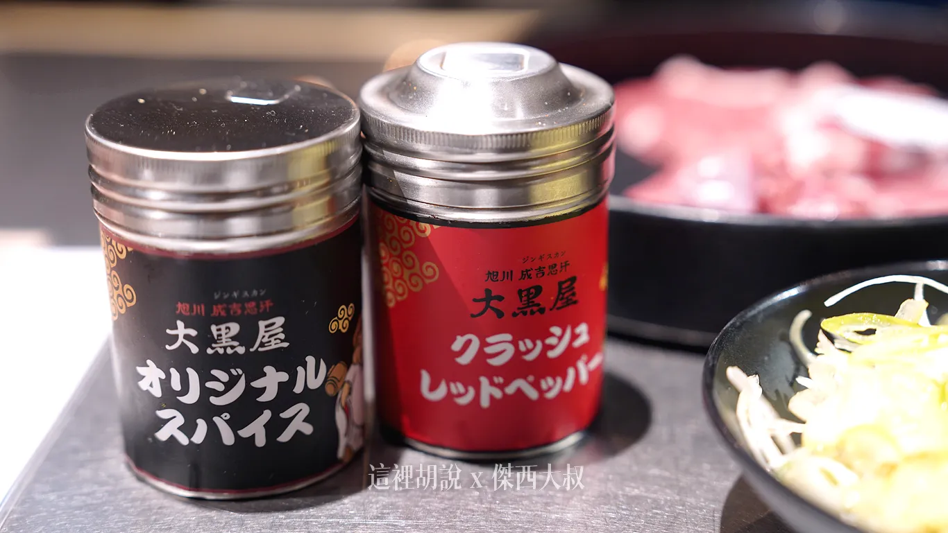 左側黑色：大黑屋原創香料 (Daikokuya Original Spice) 招牌調味料，通常由多種香料調配而成，專門用來提升烤羊肉的鮮味。右邊紅罐： 大黑屋碎紅椒粉 (Daikokuya Crushed Red Pepper) 適合喜歡辛辣口味的饕客灑在烤肉或沾醬中使用。