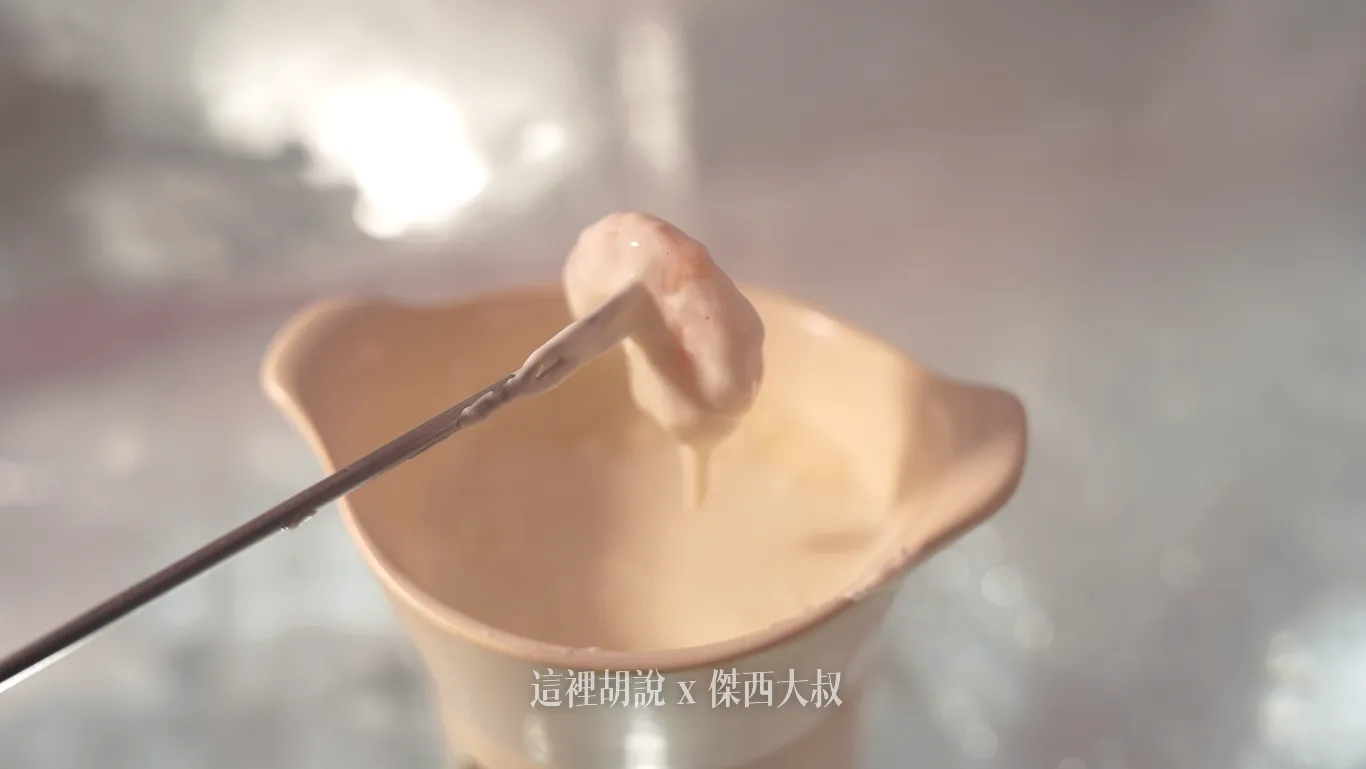 金屬長叉叉起裹滿濃稠醬汁的配料,從米黃色陶製起司鍋上方緩緩提起,呈現加熱烹煮後的誘人質地。 金屬長叉叉起裹滿濃稠醬汁的配料,從米黃色陶製起司鍋上方緩緩提起,呈現加熱烹煮後的誘人質地。