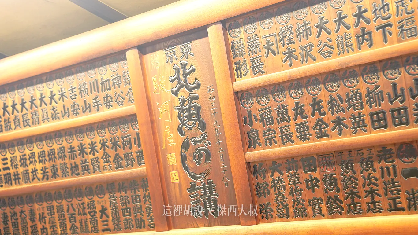 牆上掛著一面排滿密密麻麻小木牌、充滿歲月痕跡的巨型木製牌匾。這不僅僅是一件古董裝飾，它是駿河屋從江戶時代一路走來的「指定旅宿特約看板」（日文稱：講看板），更是這棟建築曾作為百年旅館的歷史鐵證。