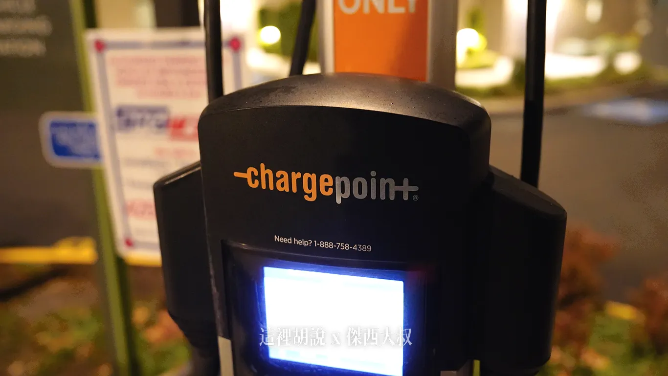 西雅圖機場 Element Hotel 停車場設置的 ChargePoint 電動車充電樁，黑色機身上方印有品牌標誌與客服專線，下方螢幕亮起並懸掛充電孔設備。