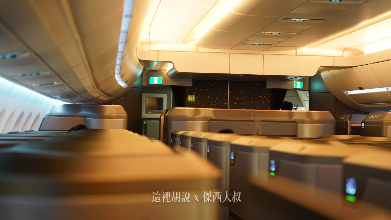 星宇航空客艙在暖黃與間接光映照下，商務艙座位整齊排列於走道兩側，最前方明顯高出一截的隔板包廂則是頭等艙區域。