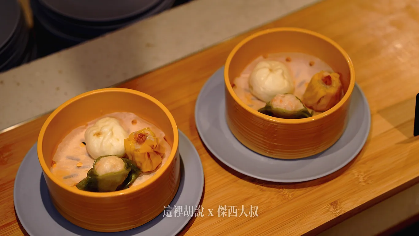 熱食吧台上擺放著特製蒸籠，黃色圓形蒸籠內墊著蒸紙，盛裝著白色小包子、綠色蝦仁燒賣以及黃色燒賣等三種不同風味的點心，
