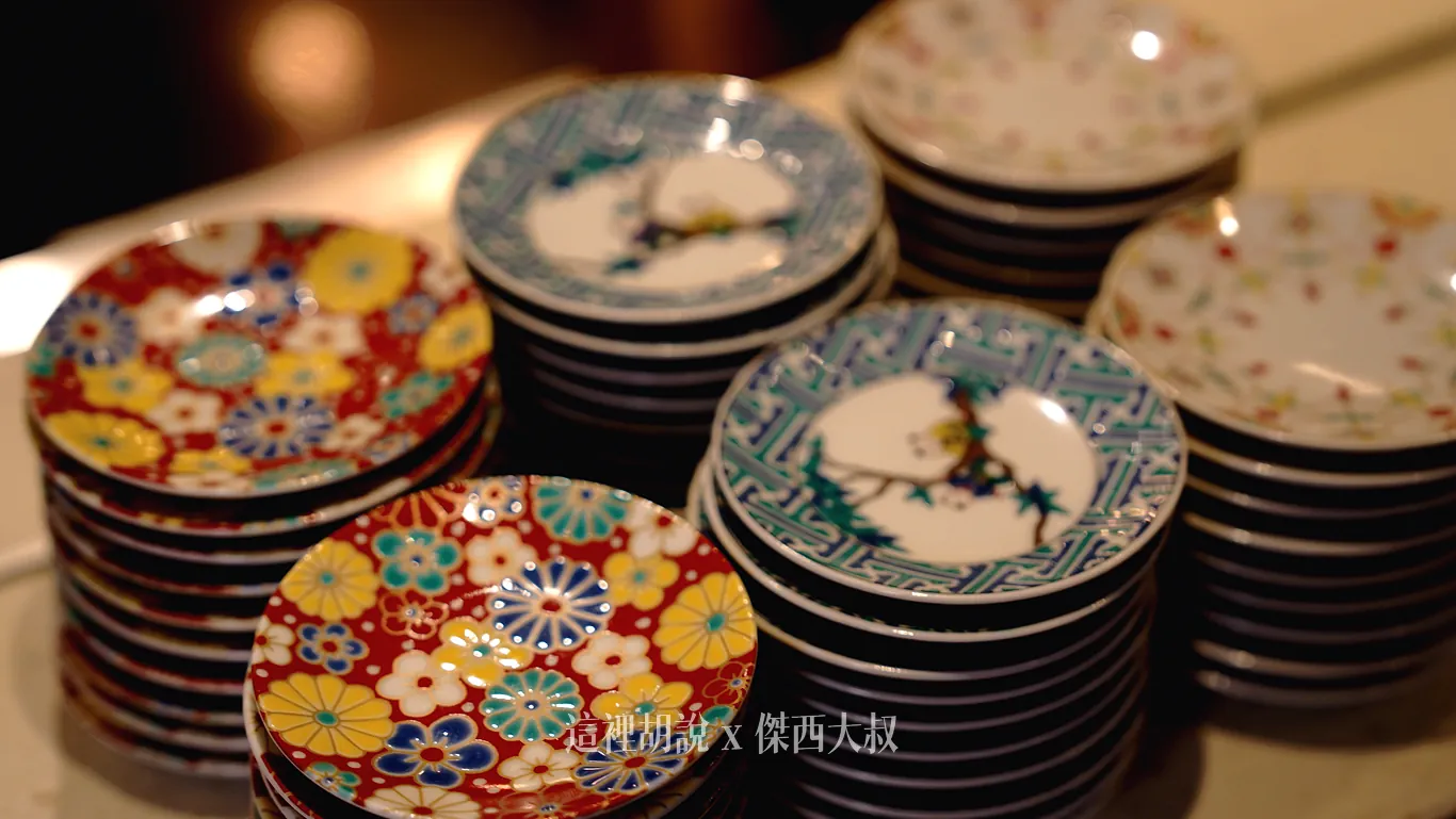 吧台上整齊疊放著各式沾料小碟子，瓷盤表面繪有鮮豔菊花花紋、幾何圖騰與古典松木等日式中華特色圖樣供房客自由取用。