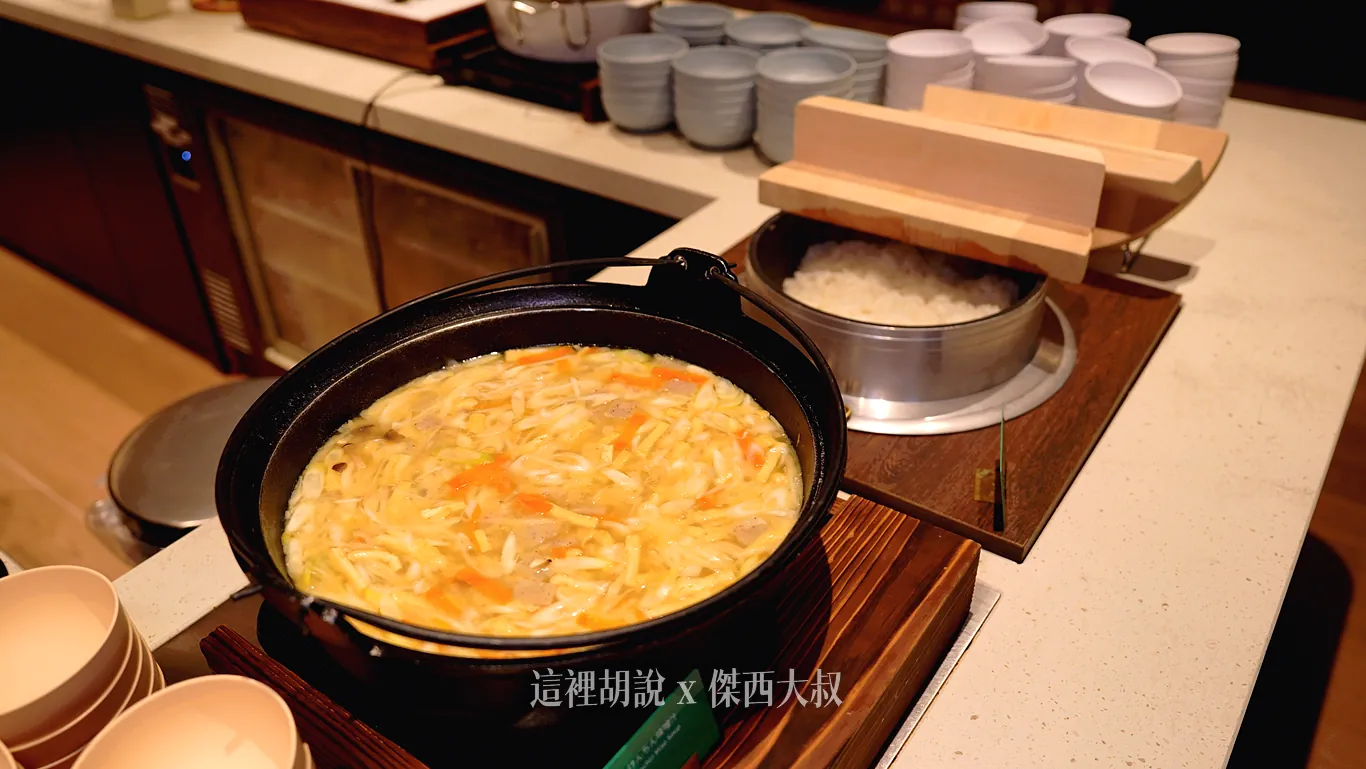 OMO7橫濱早餐吧台上以傳統大釜盛裝熱騰騰的白飯，前方黑色鑄鐵鍋內則裝滿加入大量蔬菜熬煮的味噌湯，後方整齊備有多款湯碗供取用。
