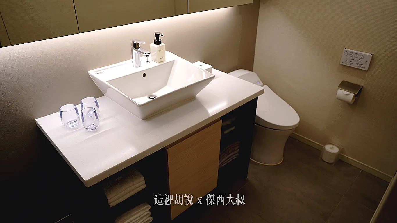 客房浴室內配有白色方形洗手臺與免治馬桶,檯面上整齊擺放著透明漱口杯與洗手乳,下方收納櫃則收納了乾淨的毛巾備品。 客房浴室內配有白色方形洗手臺與免治馬桶,檯面上整齊擺放著透明漱口杯與洗手乳,下方收納櫃則收納了乾淨的毛巾備品。