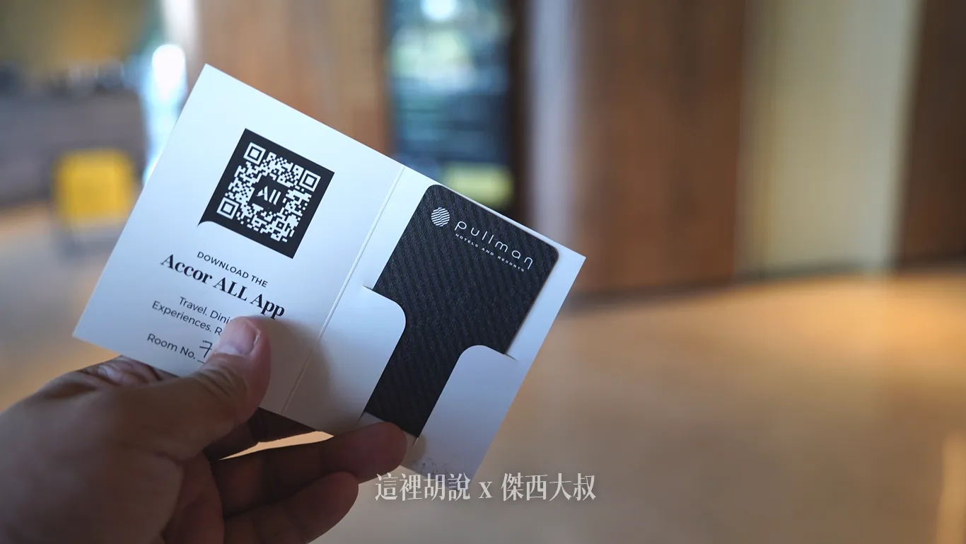 手持展開的奧克蘭機場鉑爾曼飯店白色紙質房卡套，印有品牌標誌的黑色細紋感應房卡。