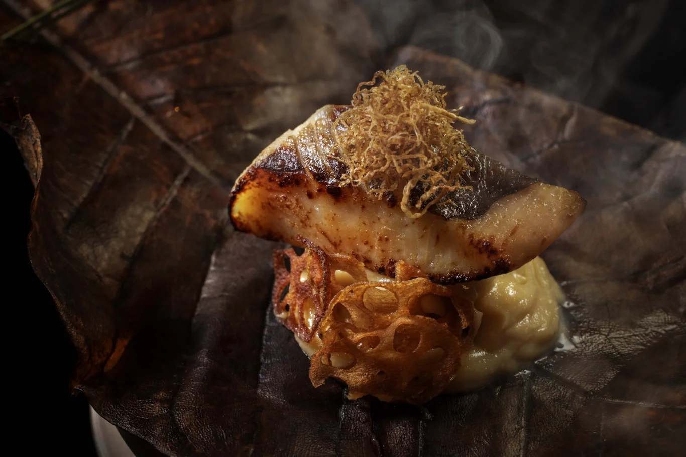 烤物「冬嶺」：嚴選初冬油脂漸趨豐腴的銀鯧（真名鰹），經幽庵醬汁醃漬後炭火慢烤；盛放於塗抹香醇吟釀味噌的朴葉上，並置於溫熱石板上保溫呈獻。入口兼具幽庵地的微酸清香與朴葉味噌的焦香，再佐以細切絹生薑提味，風味雅緻豐富。