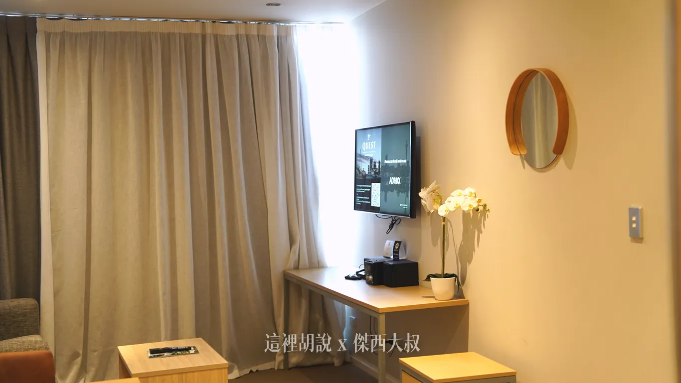 奧克蘭Quest on Hobson公寓式酒店的客廳內,電視懸掛在較高的牆面位置,下方配置簡約的長型書桌,桌上擺放白色蘭花盆栽與音響設備。 奧克蘭Quest on Hobson公寓式酒店的客廳內,電視懸掛在較高的牆面位置,下方配置簡約的長型書桌,桌上擺放白色蘭花盆栽與音響設備。