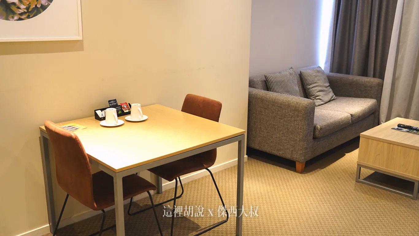 奧克蘭Quest on Hobson公寓式酒店客廳角落擺設一張簡單的小餐桌,搭配兩張皮革色單椅,桌面上備有茶包備品與馬克杯,後方則銜接灰色布質沙發與茶几。 奧克蘭Quest on Hobson公寓式酒店客廳角落擺設一張簡單的小餐桌,搭配兩張皮革色單椅,桌面上備有茶包備品與馬克杯,後方則銜接灰色布質沙發與茶几。