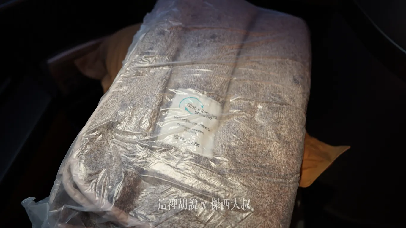星宇航空商務艙提供未拆封的大地灰雙面毛絨毛毯，透明塑膠包裝內附有標籤，清晰印著全球回收標準認證標誌與星宇航空字樣。此毛毯榮獲全球回收標準(Global Recycled Standard）的認證，100%由回收寶特瓶製作而成。